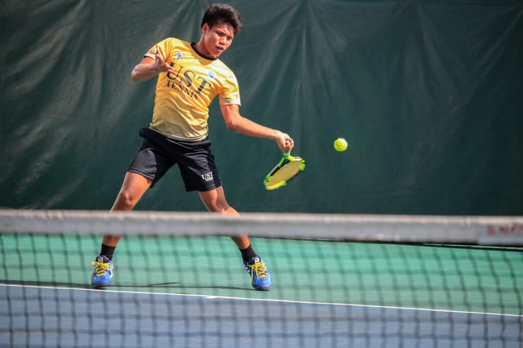 Male tennis player in action on an outdoor court, with focus on a dynamic forehand shot.